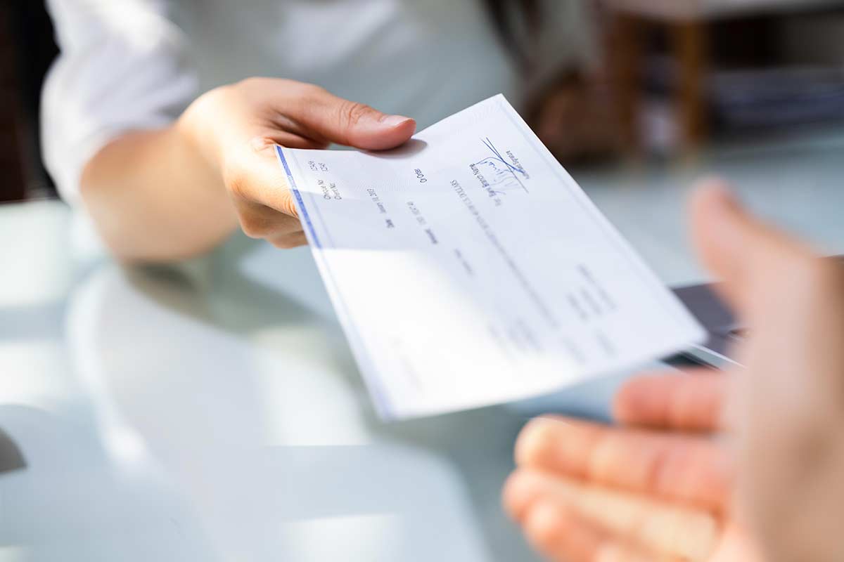 hand giving payroll compensation paycheck 1200