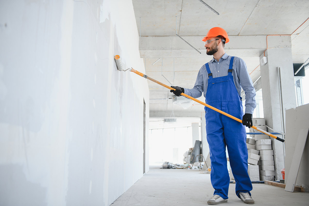 painter in uniform paints the wall